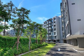 A modern apartment building with multiple balconies, a parking area, and a well-maintained garden. - Cassia Residences, Two-Bedroom 1502 D Deluxe Lake (Choeng Thale)