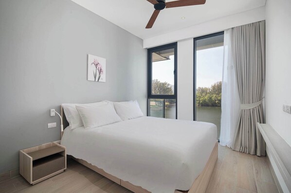 A bedroom with a bed, a ceiling fan, a window with curtains, and a painting on the wall.