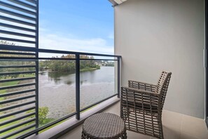 A balcony with a view of a river and greenery, featuring wicker furniture. - Cassia Residences, Two-Bedroom 2401 D Deluxe Lake (Choeng Thale)