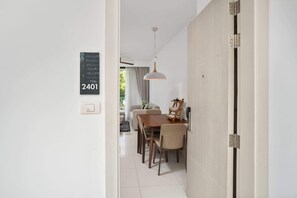 Een modern interieur met een eethoek, een hanglamp en een deur met een nummer.