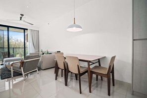 Een moderne eetruimte met een houten tafel en stoelen, een plafondventilator en grote ramen met uitzicht op het landschap.
