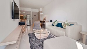 Ein modernes Wohnzimmer mit einer Couch, einem Couchtisch und einem an der Wand befestigten Fernseher.