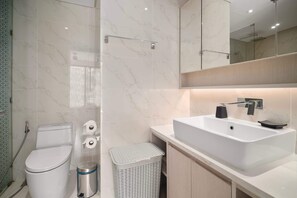 Une salle de bain moderne avec des toilettes blanches, un lavabo et un espace douche.