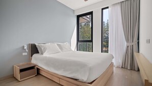 Ein modernes Schlafzimmer mit einem großen Bett, integriertem Nachttisch und einem Fenster mit Vorhängen.