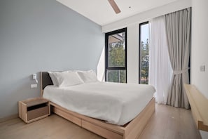 Une chambre moderne avec un grand lit, une table de chevet intégrée et une fenêtre avec des rideaux.