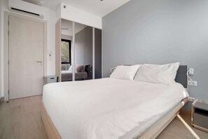 Un dormitorio moderno con una cama grande, un armario y vistas a través de un ventanal.