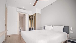 Een moderne slaapkamer met een groot bed, een plafondventilator en een inloopkast.