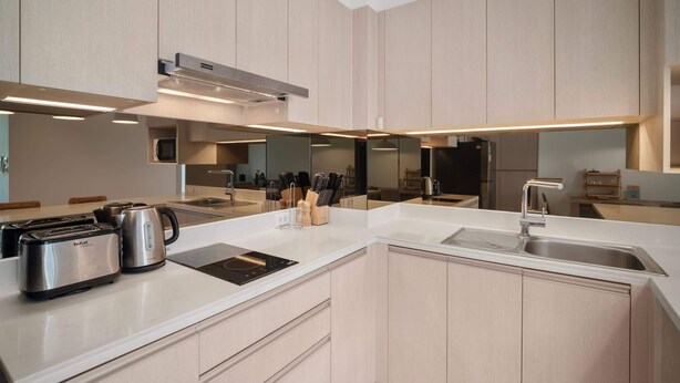 A modern kitchen with a central island, stainless steel appliances, and a large mirror. - Cassia Residences, Two-Bedroom 2610 D Premium (Choeng Thale)