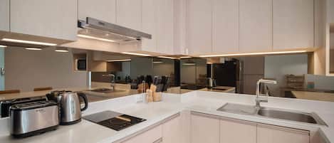Una cocina moderna con una isla central, electrodomésticos de acero inoxidable y un espejo grande.