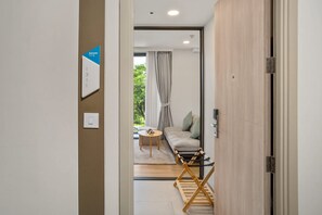 Ein modernes Interieur mit einer Holztür, einem kleinen Tisch, einer Couch und Blick ins Freie durch ein Fenster.