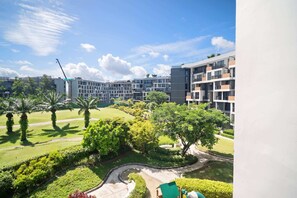 Un ensemble immobilier résidentiel doté de nombreux balcons, d’un jardin aménagé avec des palmiers et offrant une vue sur un ciel dégagé.