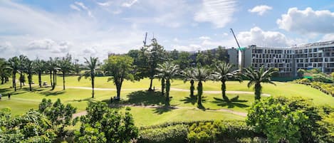 Un espace paysager agrémenté de palmiers, un terrain de golf et un bâtiment à plusieurs étages.