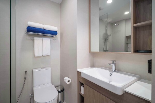 Un baño moderno con inodoro, ducha, lavabo y espejo.