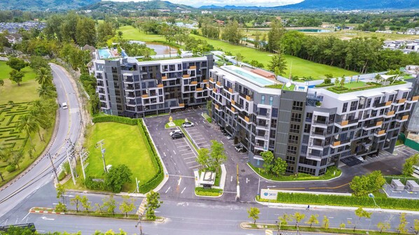 A modern apartment complex with multiple buildings, a parking area, and surrounding greenery.
