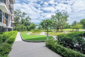 A landscaped courtyard with a curved pathway, green lawns, and trees.
