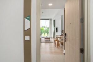 A hallway leading to a dining area with a view of greenery outside.