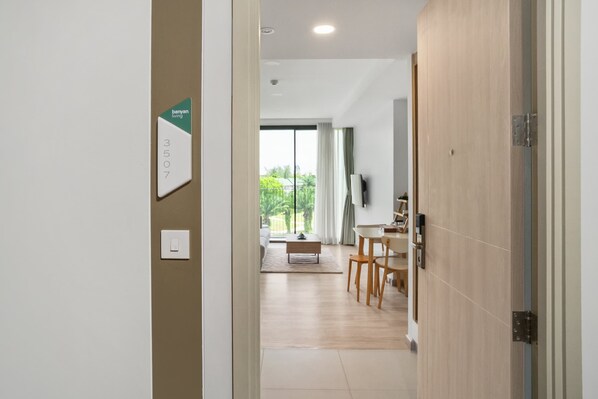 A hallway leading to a dining area with a view of greenery outside.