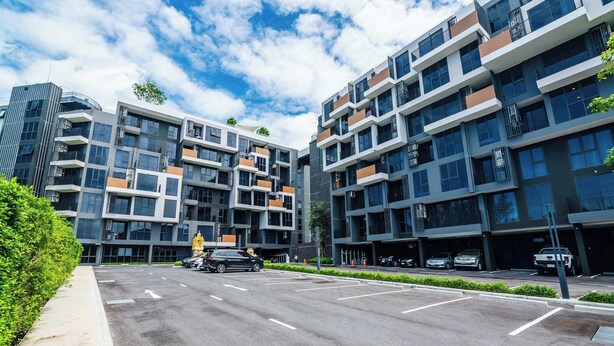 Un edificio moderno de varios pisos con un área de estacionamiento al frente.