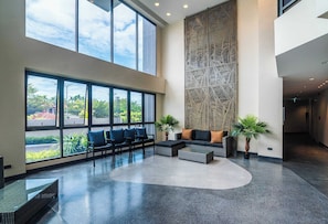 Een ruime lobby met grote ramen, een hoge plafond en een decoratieve wand.