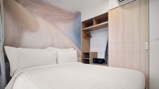Une chambre avec un grand lit, une armoire dotée de nombreuses étagères et un mur au motif imitant le grain du bois.