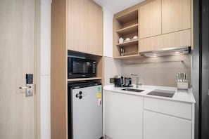 Een kleine keuken met een magnetron, koelkast en spoelbak.