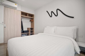Een moderne slaapkamer met een groot bed, een garderobe en een wandkunstwerk.