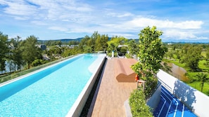 Ein langer Pool mit Holzterrasse und Blick auf einen Fluss und Grünflächen.