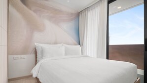 Une chambre moderne avec un grand lit, une vue sur le ciel par la fenêtre et un décor mural original.