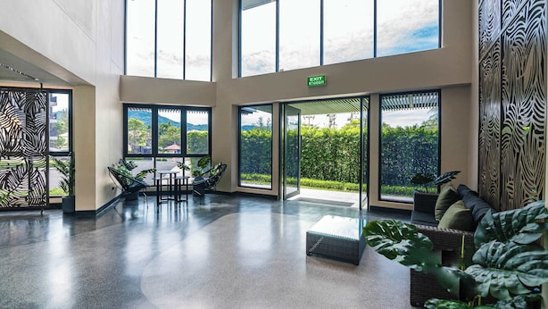 Un hall d’entrée spacieux, doté de grandes fenêtres, d’un espace détente et d’un panneau indiquant la sortie.