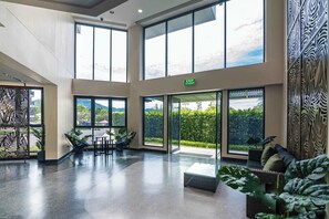Un vestíbulo amplio con ventanas grandes, una zona de estar y una señal de salida.