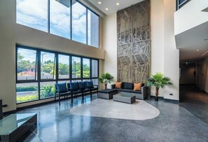 A spacious lobby with large windows, a high ceiling, and a decorative wall.