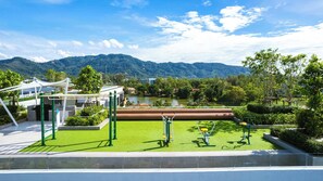 Un parque con equipo de ejercicio, un lago y montañas al fondo.