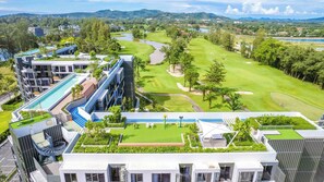 A modern hotel with a rooftop pool, a golf course, and a view of the surrounding landscape.