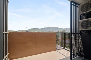 A balcony with a view of distant mountains, a metal drying rack, and a black railing. - Skypark Aurora, One Bedroom 3709 1Bx Premium (Choeng Thale)