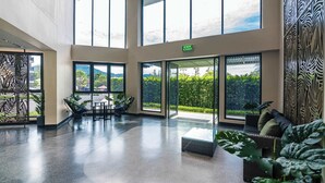 Un vestíbulo amplio con ventanas grandes, una zona de estar y una señal de salida.
