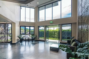 A spacious lobby with large windows, a seating area, and an exit sign.