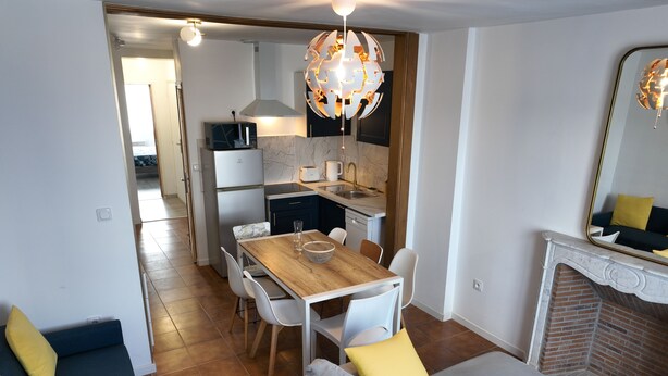 A modern living room with a dining area, a fireplace, and a kitchen in the background. - Large city apartment with 2 private indoor parking spaces (Beuvrages)