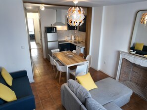 Un salon moderne avec un coin repas, une cheminée et une cuisine en arrière-plan.