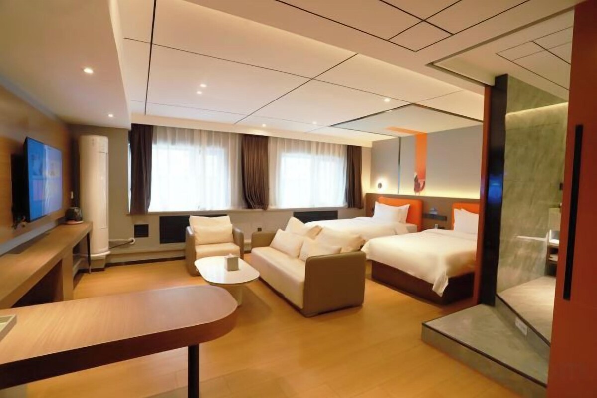 Habitación de hotel con sofá, dos camas, televisión y escritorio.