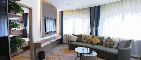 A modern living room with a sofa, a coffee table, and a TV mounted on the wall.
