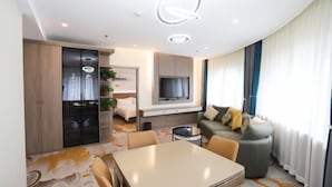 A modern living room with a sofa, a dining table, and a TV mounted on the wall. - Peoples Hotel (Lanzhou)