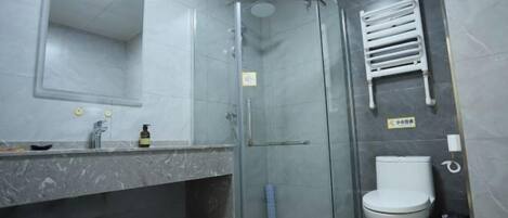 Un baño con ducha de vidrio, inodoro, lavabo con espejo y un perchero para toallas.