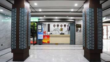 Un área de recepción con mostrador de mármol, una mesa de recepción y una puerta de vidrio que da a la recepción.
