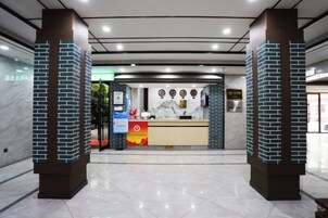 Un área de recepción con mostrador de mármol, una mesa de recepción y una puerta de vidrio que da a la recepción.