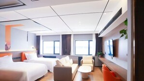 A hotel room with two beds, a sofa, a coffee table, and a TV on the wall. - Peoples Hotel (Lanzhou)