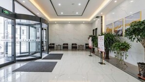 A hotel lobby with a revolving door, seating area, and potted plants. - Peoples Hotel (Lanzhou)