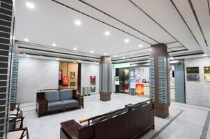 Un vestíbulo de hotel con mostrador de recepción, zona de estar y mostrador.