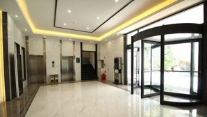 A modern lobby with a marble floor, elevators, a glass revolving door, and a staircase. - Peoples Hotel (Lanzhou)