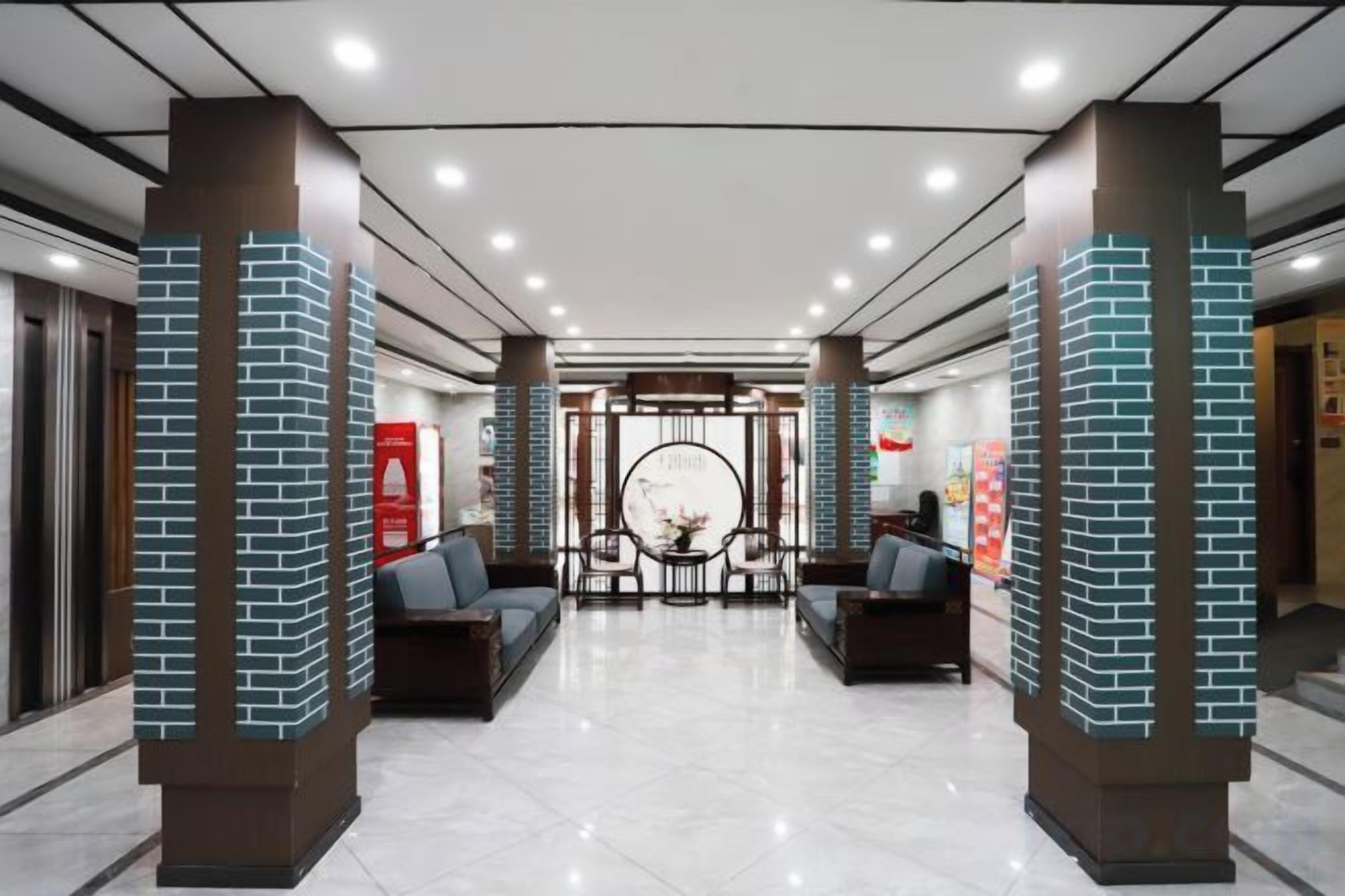 A lobby with a reception desk, seating area, and a decorative wall with a circular pattern.