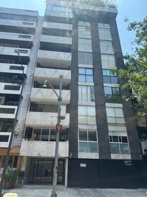 A multi-story building with a modern architectural design, featuring balconies and large windows.